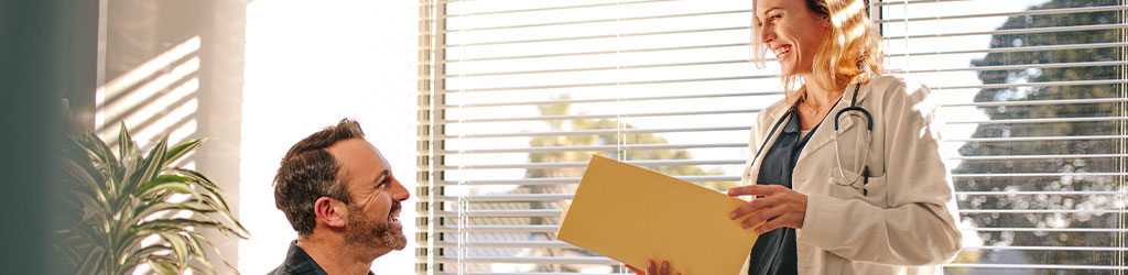 Paciente masculino y doctora en consulta mostrando unos informes